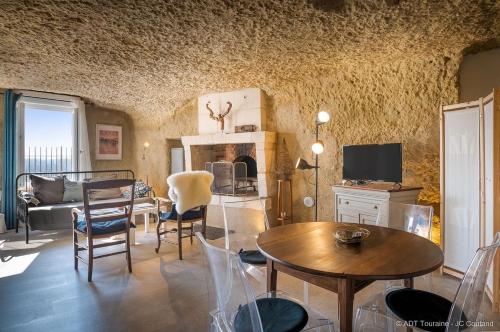 sala de estar con mesa, sillas y TV en La cavée du coteau, petit cocon troglodytique en Vouvray