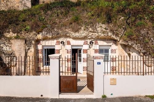 un portail en face d'un bâtiment avec une clôture dans l'établissement La cavée du coteau, petit cocon troglodytique, à Vouvray