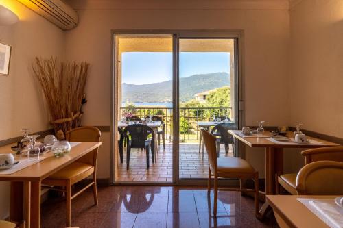 a restaurant with tables and a view of a balcony at Hotel Hibiscus in Propriano