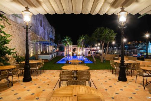 a patio with tables and chairs and a pool at night at Vila Origens Boutique Hotel Albufeira – Adults Only in Albufeira