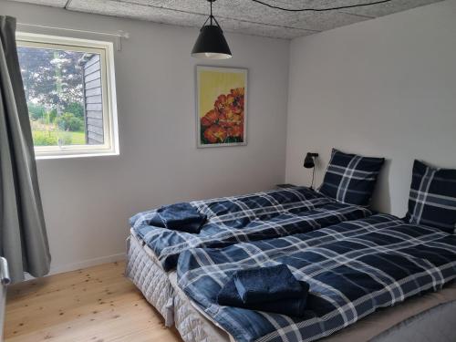 a bedroom with a bed with a blue plaid blanket at Agermosegaard in Assens
