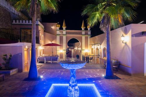 a fountain in the middle of a courtyard with palm trees at Vila Origens Boutique Hotel Albufeira – Adults Only in Albufeira