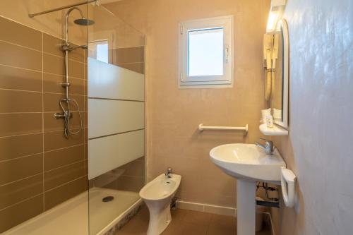 a bathroom with a sink and a toilet and a shower at Hotel Hibiscus in Propriano