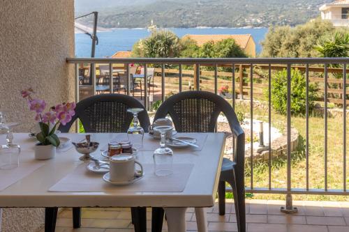 a white table with chairs and a view of the ocean at Hotel Hibiscus in Propriano
