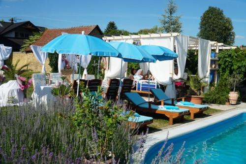 a pool with blue umbrellas and lounge chairs next to a pool at Marija in Srbobran