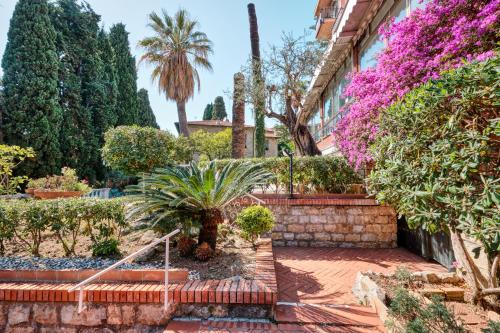 a garden in front of a building with trees and flowers at Hotel Astoria in Bordighera