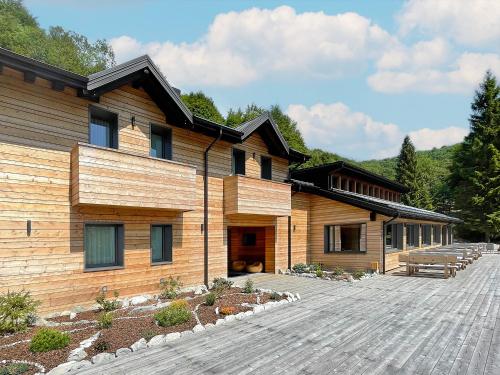 un edificio de madera con una terraza de madera delante de él en Relais Sauc & SPA - Agriturismo, en Piancavallo