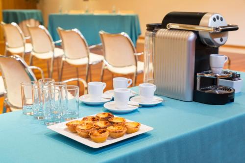 a table with a plate of pastries and a coffee maker at Hotel Dom Goncalo & Spa in Fátima
