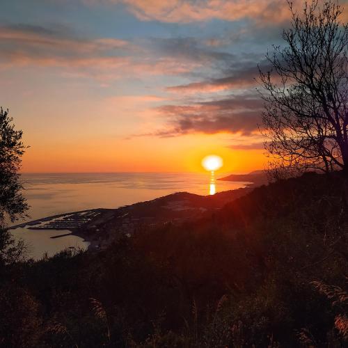 a sunset over the ocean with the sun on a hill at La casa rosa in Lingueglietta