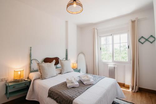 sypialnia z dużym białym łóżkiem z ręcznikami w obiekcie tuGuest Halcón Apartment w Grenadzie