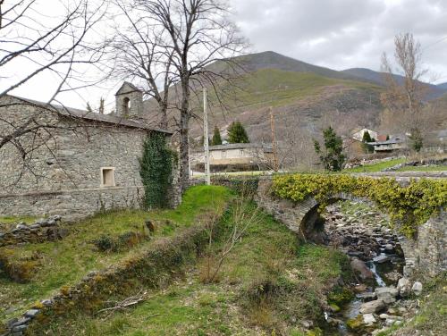 a stone house with a bridge over a river at CAMPING LA ZARAPICA - Palacios del Sil in Palacios del Sil