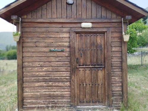 a wooden shed with a wooden door in a field at CAMPING LA ZARAPICA - Palacios del Sil in Palacios del Sil