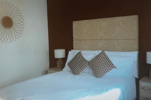 a bedroom with a white bed with two pillows at Welsh Getaway Home No 1 - 10 mins to Bike Park Wales in Merthyr Tydfil