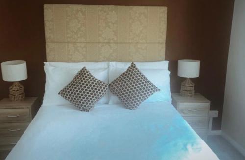 a bedroom with a bed with two pillows and two lamps at Welsh Getaway Home No 1 - 10 mins to Bike Park Wales in Merthyr Tydfil