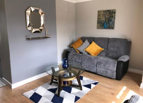 a living room with a couch and a glass table at Welsh Getaway Home No 1 - 10 mins to Bike Park Wales in Merthyr Tydfil