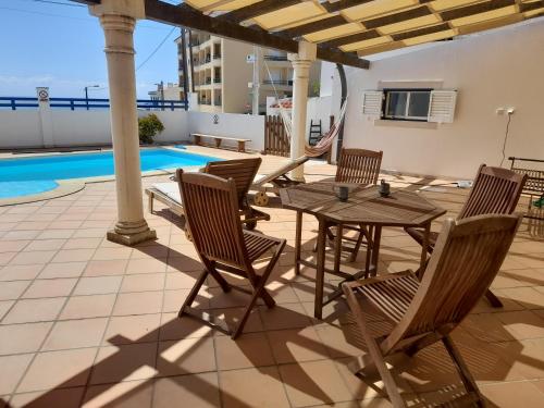 a patio with a table and chairs next to a pool at Villa Alegria in Ericeira