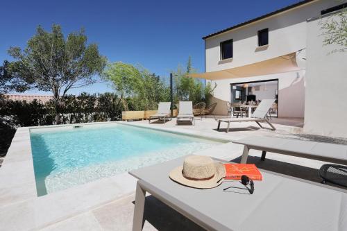 - un chapeau assis sur une table à côté d'une piscine dans l'établissement Au clos de Manon, à Vers-Pont-du-Gard