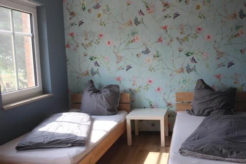 a bedroom with two beds and a floral wallpaper at Landperle Darze in Altenhof