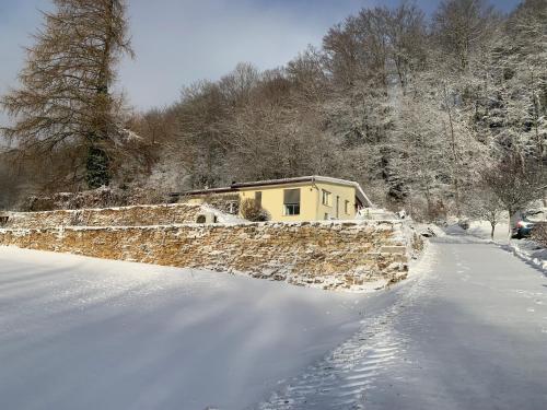 a house with a stone wall in the snow at Maison chez Louis in Asuel
