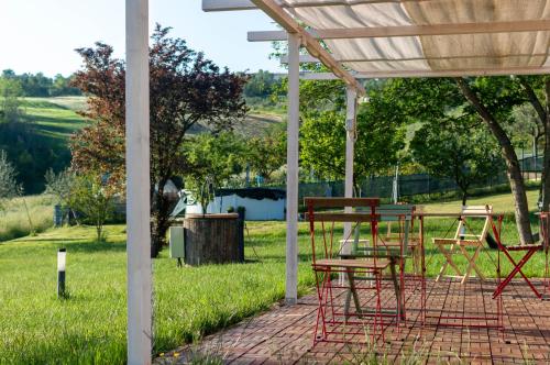 a patio with red chairs and a table in the grass at La Silvana B&B in Coriano