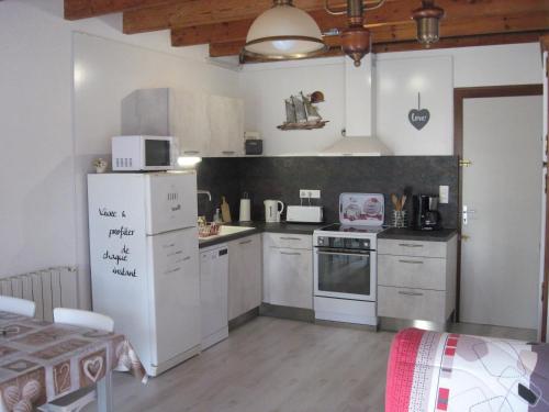Il comprend une cuisine équipée d'appareils électroménagers blancs et d'un réfrigérateur blanc. dans l'établissement Gîte Le COZILLON, à Cozes