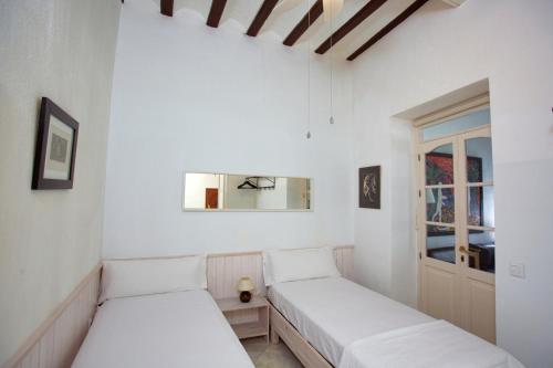 2 Betten in einem Zimmer mit weißen Wänden und einem Fenster in der Unterkunft Barroso 4 by 7Escalones in Rota