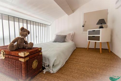 a teddy bear sitting on a trunk in a bedroom at Le Clos des Eucalyptus in Plan-de-la-Tour