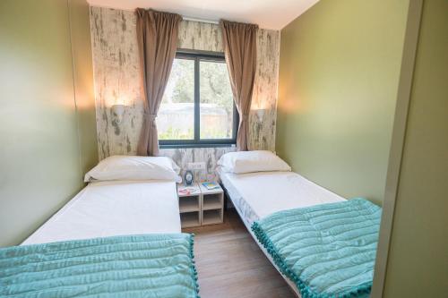 two beds in a small room with a window at Camping Village Riva Blu in Padenghe sul Garda