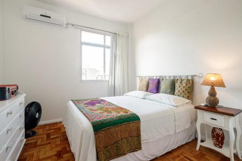 a white bedroom with a bed and a window at Comodidade no Coração de Floripa in Florianópolis