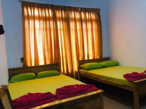 2 camas con almohadas verdes en una habitación en New Elkaduwa LOFT Hotel, en Wattegama