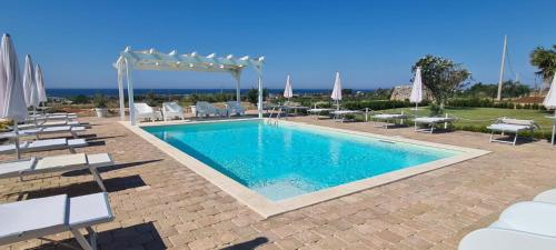 a swimming pool with chairs and a canopy and a pool at B&B Giglio Marino in Salve