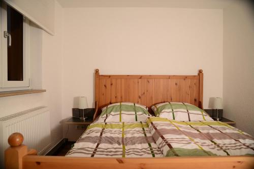 a bedroom with a wooden bed with two pillows at Ferienanlage Markus Nitsch in Bärenstein