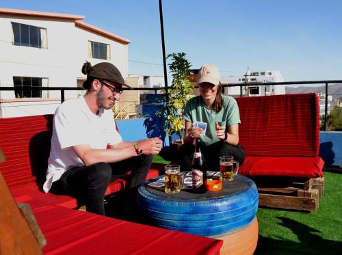 twee mannen op een patio met een tafel met drankjes bij Econunay Hostels in Arequipa