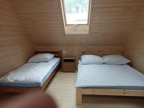 two beds in a wooden room with a window at Domki z widokiem na morze u Jasia in Trzęsacz