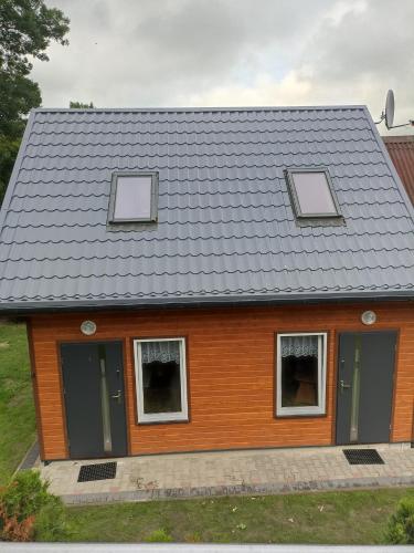 a house with three windows and a gray roof at Domki z widokiem na morze u Jasia in Trzęsacz