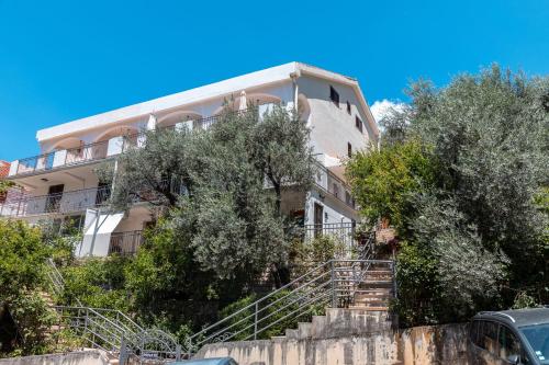 un edificio de apartamentos con escaleras delante de los árboles en Olive Garden Apartments, en Sveti Stefan