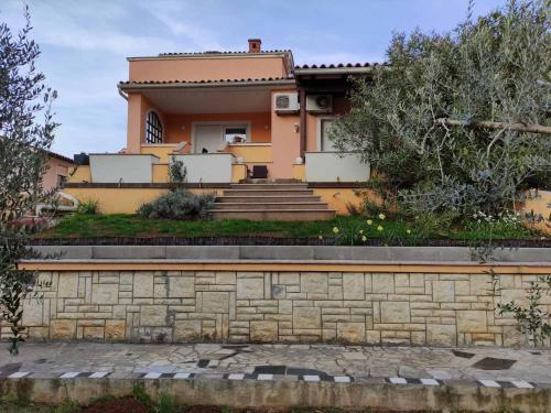 a yellow house with a stone wall and stairs at Apartmani Viktorija in Fažana