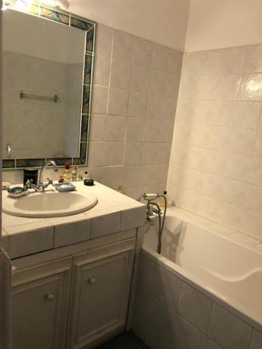 een badkamer met een wastafel, een bad en een spiegel bij Agréable maison de ville au calme avec garage in Cannes