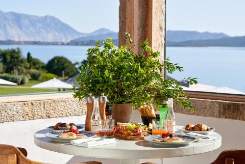 einen Tisch mit Nahrung und Blick auf das Wasser in der Unterkunft Due Lune Puntaldia Resort & Golf in San Teodoro