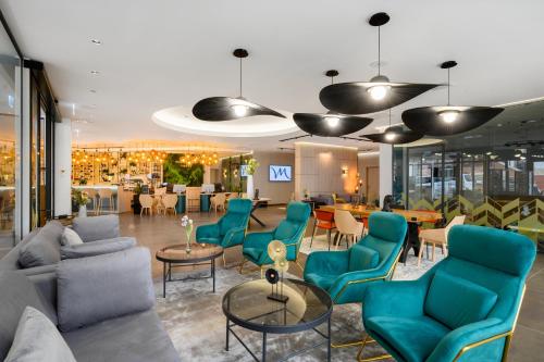 a lobby with blue chairs and tables and a restaurant at Mercure Tokaj Center in Tokaj