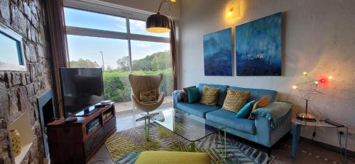 un salon avec un canapé bleu et une télévision dans l'établissement Villa Palm' Issambres 6-7 personnes, clim, avec piscine, jardin et parking privés, à La Garonnette-Plage