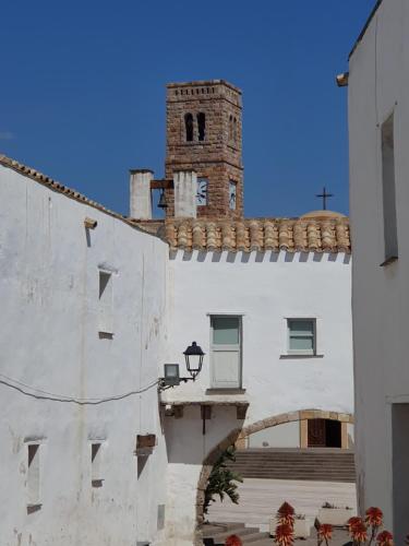 a building with a clock tower on top of it at Moon's Tower suite&rooms in Portoscuso
