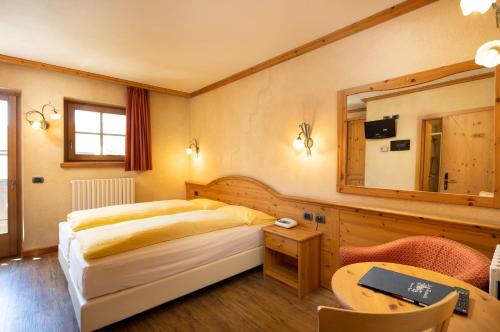 Schlafzimmer mit einem Bett, einem Spiegel und einem Tisch in der Unterkunft Hotel La Pastorella in Livigno