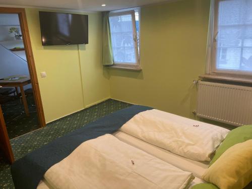 a bed in a room with a television on the wall at Hotel Garni Maaß in Braubach