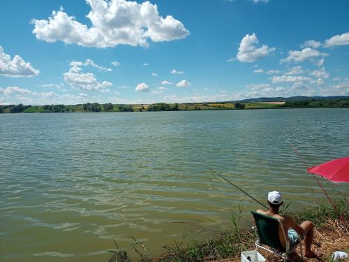 a man sitting in a chair fishing on a lake at Smeštaj Vrhovac in Vrdnik