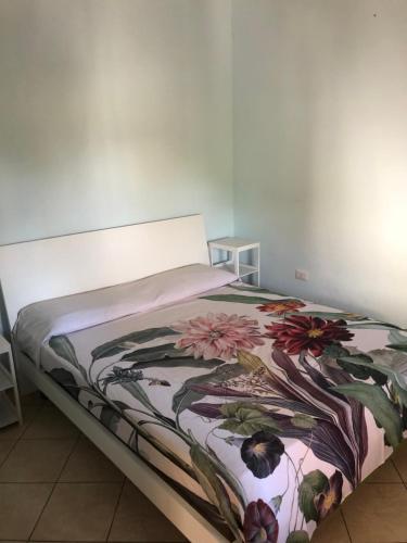 Una cama en una habitación con una manta floral. en Locazione Turistica - Il gelsomino, en Briatico