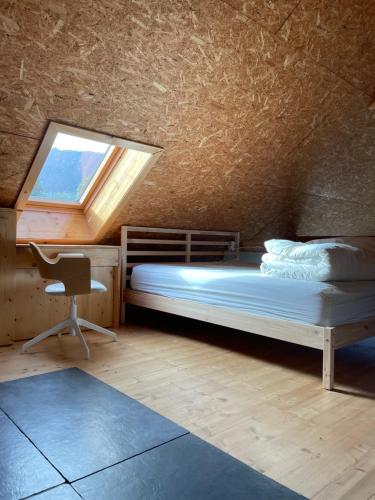 1 dormitorio con cama, ventana y silla en CHALET LA BOLLINE, en Valdeblore