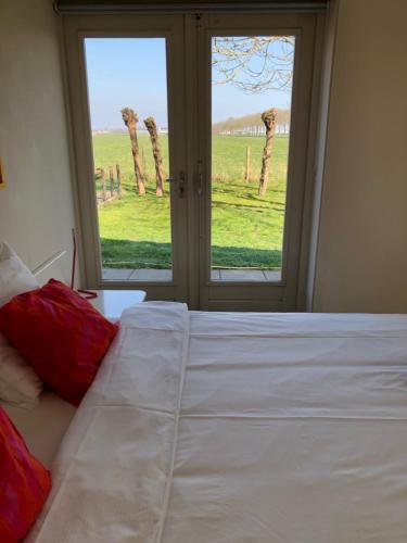 a bedroom with a bed and a window with palm trees at Lekerweg 32 in Wijdenes