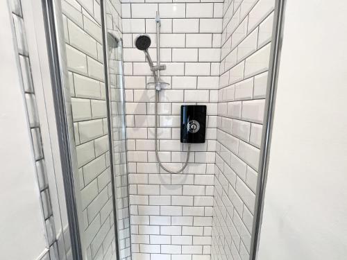 a shower with a shower head in a white tiled bathroom at 1 Bedroom Glasgow Apartment in Glasgow