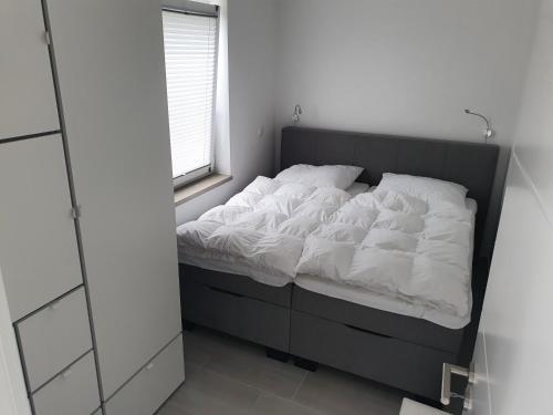 a bedroom with a bed with white sheets and a window at ***FeWo Am Achterwasser *** in Lütow